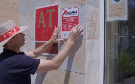 Operario de anviana colocando una placa de aprobación de todos las leyes en la puerta de una empresa.